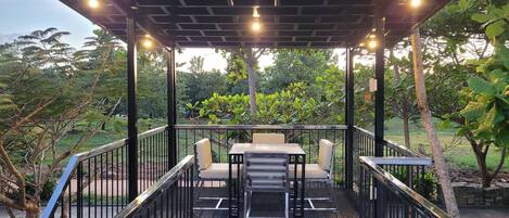 Un espace extérieur aménagé en terrasse, doté d’une pergola, de sièges et offrant une vue sur la végétation environnante.