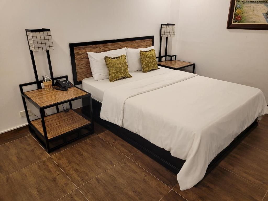 A hotel room with a bed, two bedside tables, a lamp, and a small table.