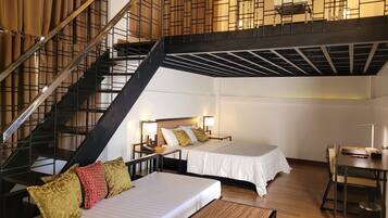 A hotel room with a staircase, two beds, a small table, and a desk.