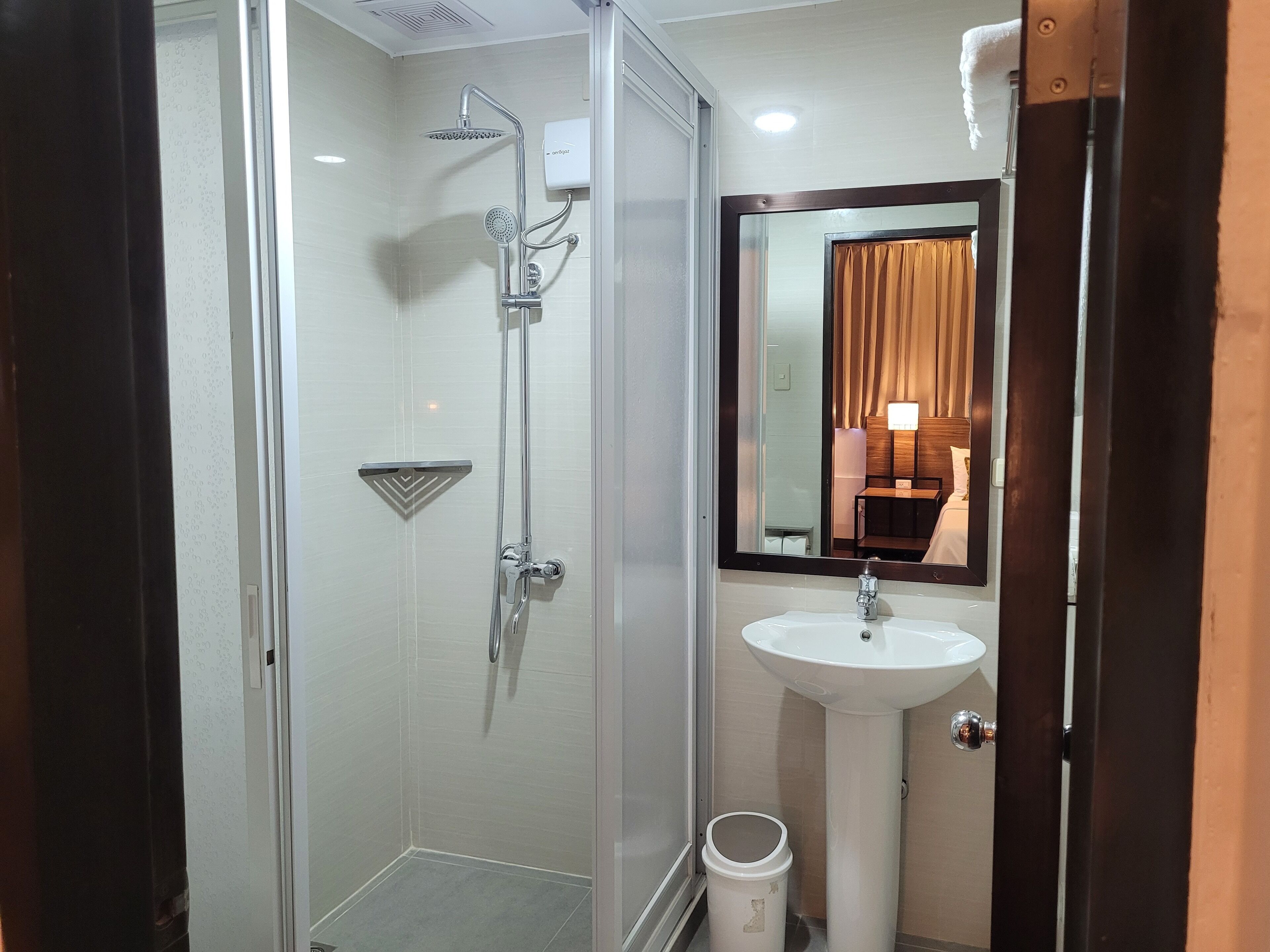A modern bathroom with a glass-enclosed shower, a white sink, and a mirror with a wooden frame.