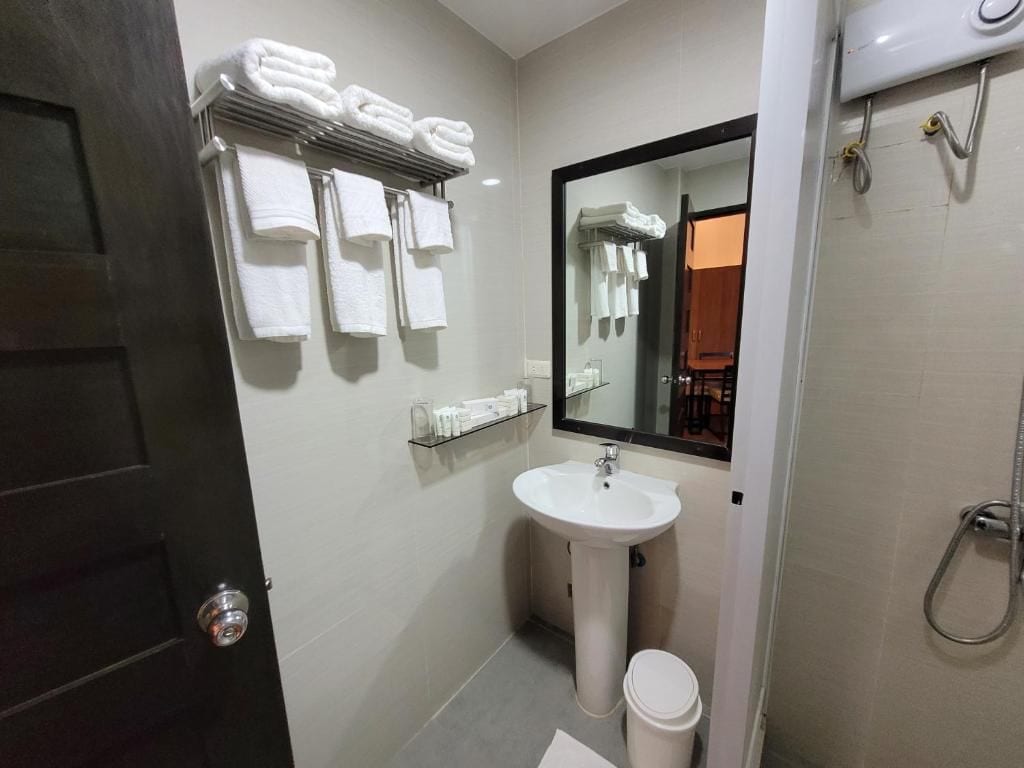 A bathroom with a sink, mirror, towel rack, and shower.