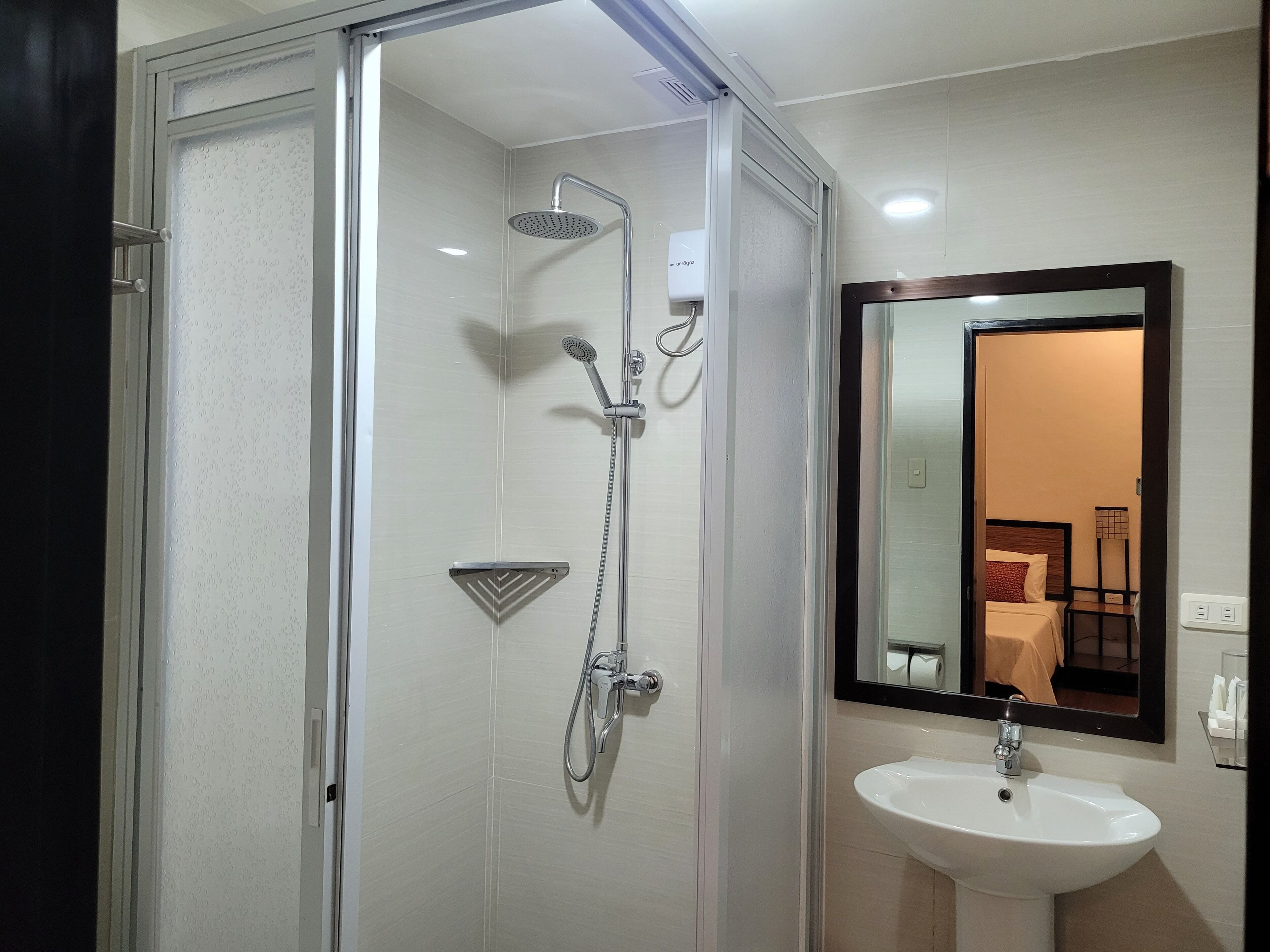A modern bathroom with a glass-enclosed shower, a white sink, and a mirror with a black frame.