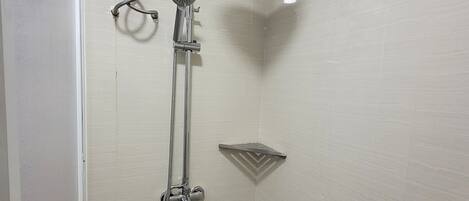 A small, enclosed shower area with a handheld showerhead, a fixed showerhead, and a control panel.