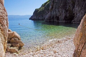 Eine felsige Küstenlinie mit klarem Wasser und einer Seilsperre.