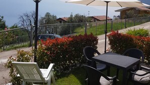 Una terrazza esterna con tavolo e sedie, un lampione e un ombrellone grande.