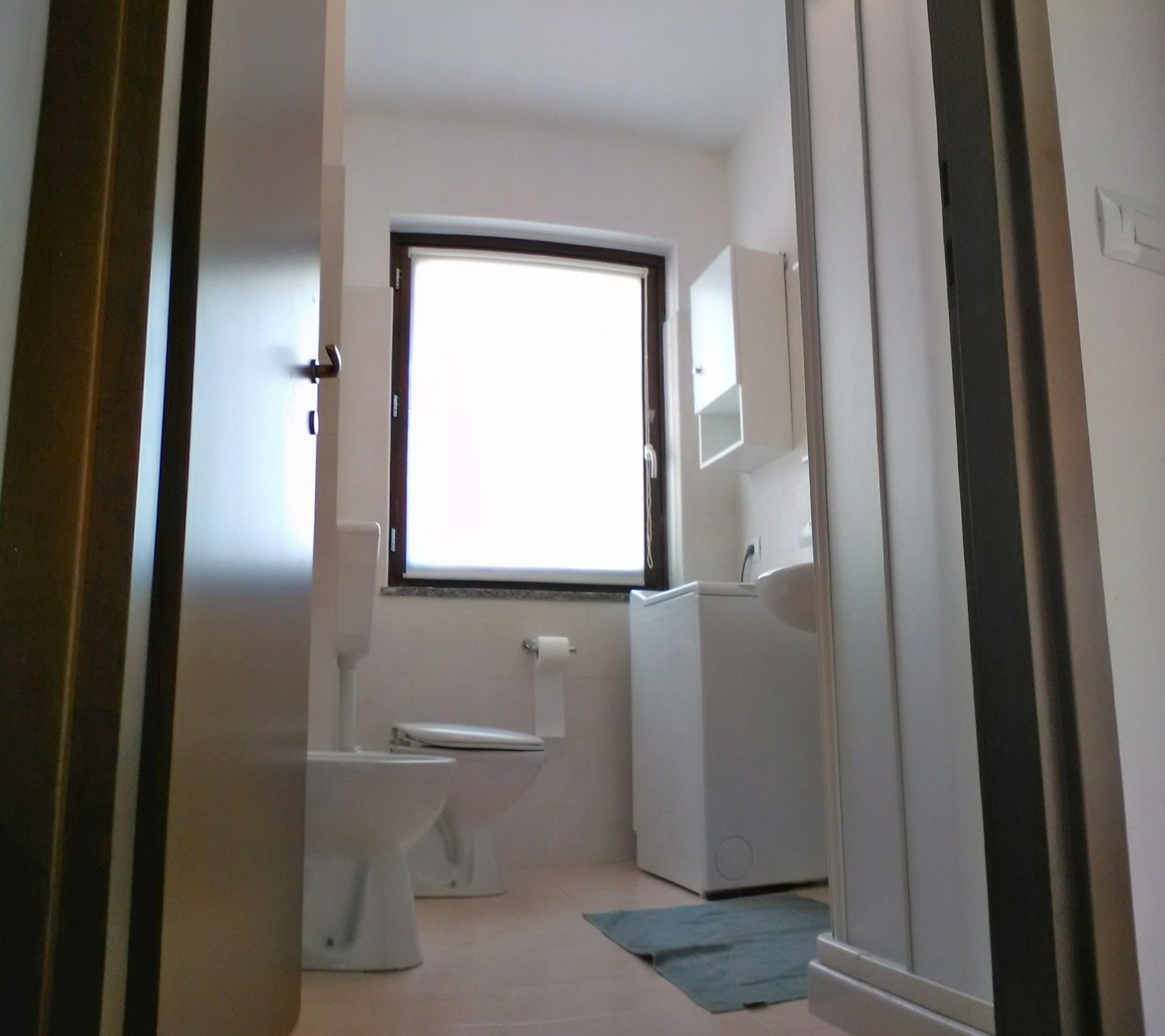 A small, compact bathroom with a toilet, a sink, and a window.