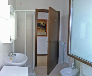 A bathroom with two sinks, a mirror, and a door leading to another room.