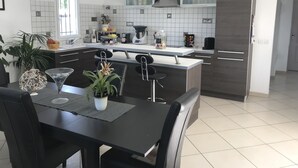 Una cocina moderna con una isla central, salpicadero de azulejos blancos y un refrigerador de madera oscura.
