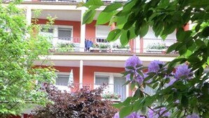 A building with balconies, surrounded by lush greenery and purple flowers. - Hotel Sonnenhof (Bad Wildbad)