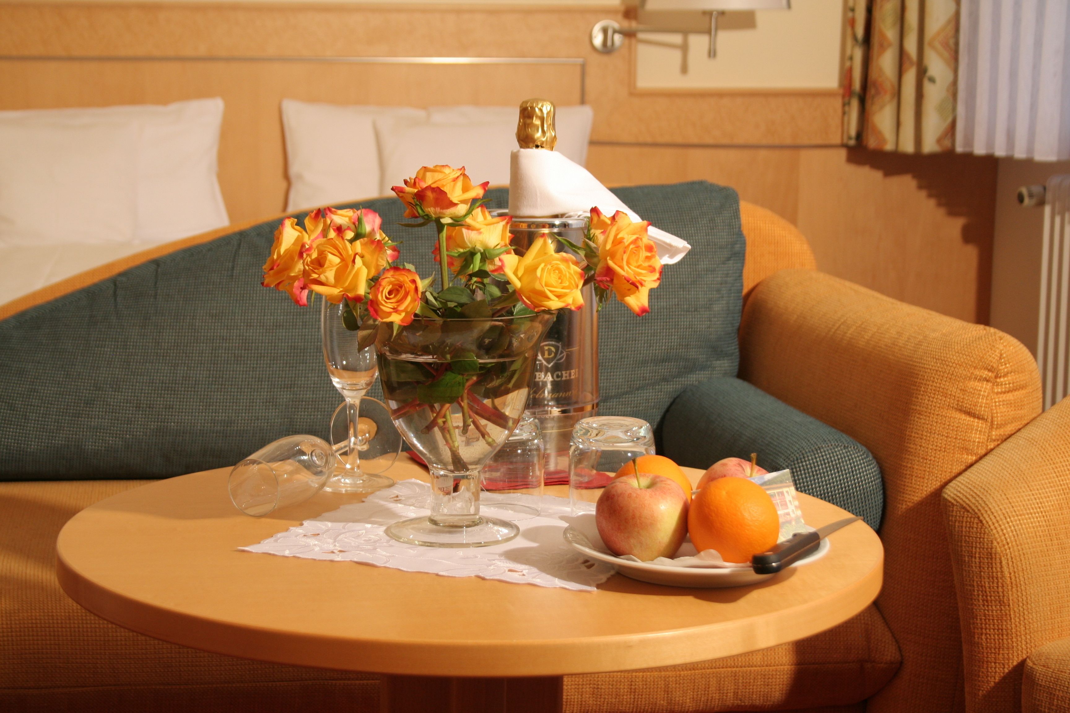 Ein Tisch mit Blumen in einer Vase, Obst auf einem Teller und einem Glas.