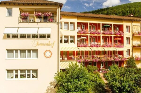 A hotel with multiple balconies adorned with flowers, a sun emblem, and a sign reading "Sonnenhof". - Hotel Sonnenhof (Bad Wildbad)