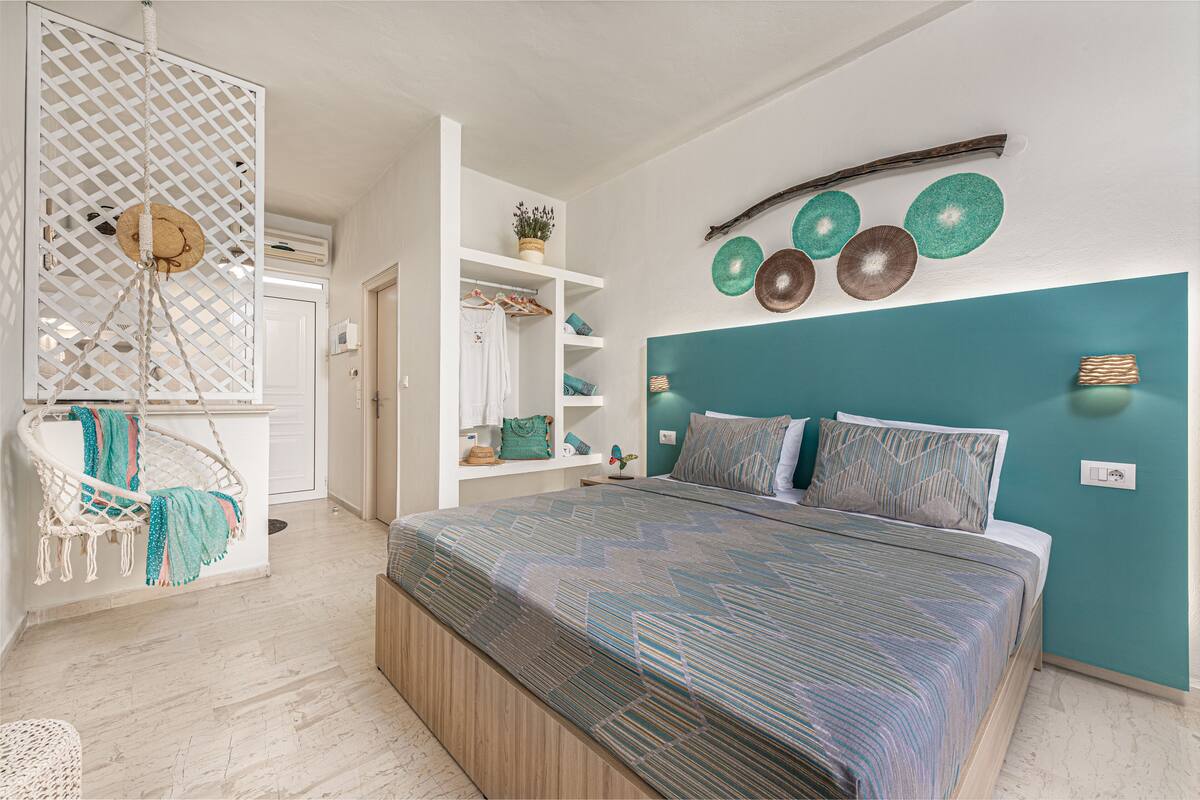 Ein Schlafzimmer mit einem Bett, einem Hängekorbsessel, einem Kleiderschrank und dekorativen Tellern an der Wand.