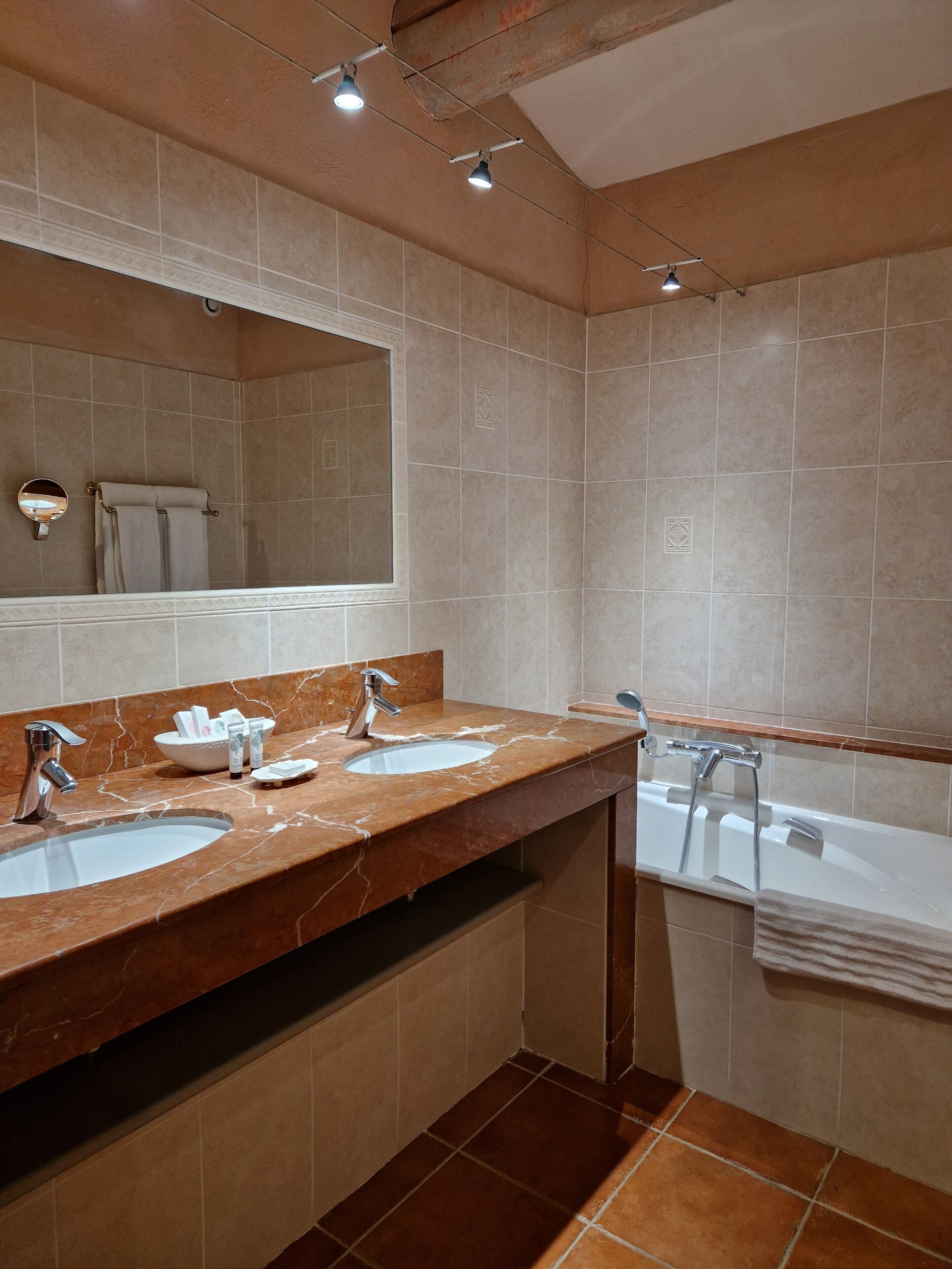 A modern bathroom with two sinks, a large mirror, and a bathtub.