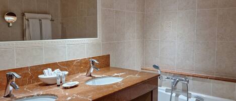 A modern bathroom with two sinks, a large mirror, and a bathtub.