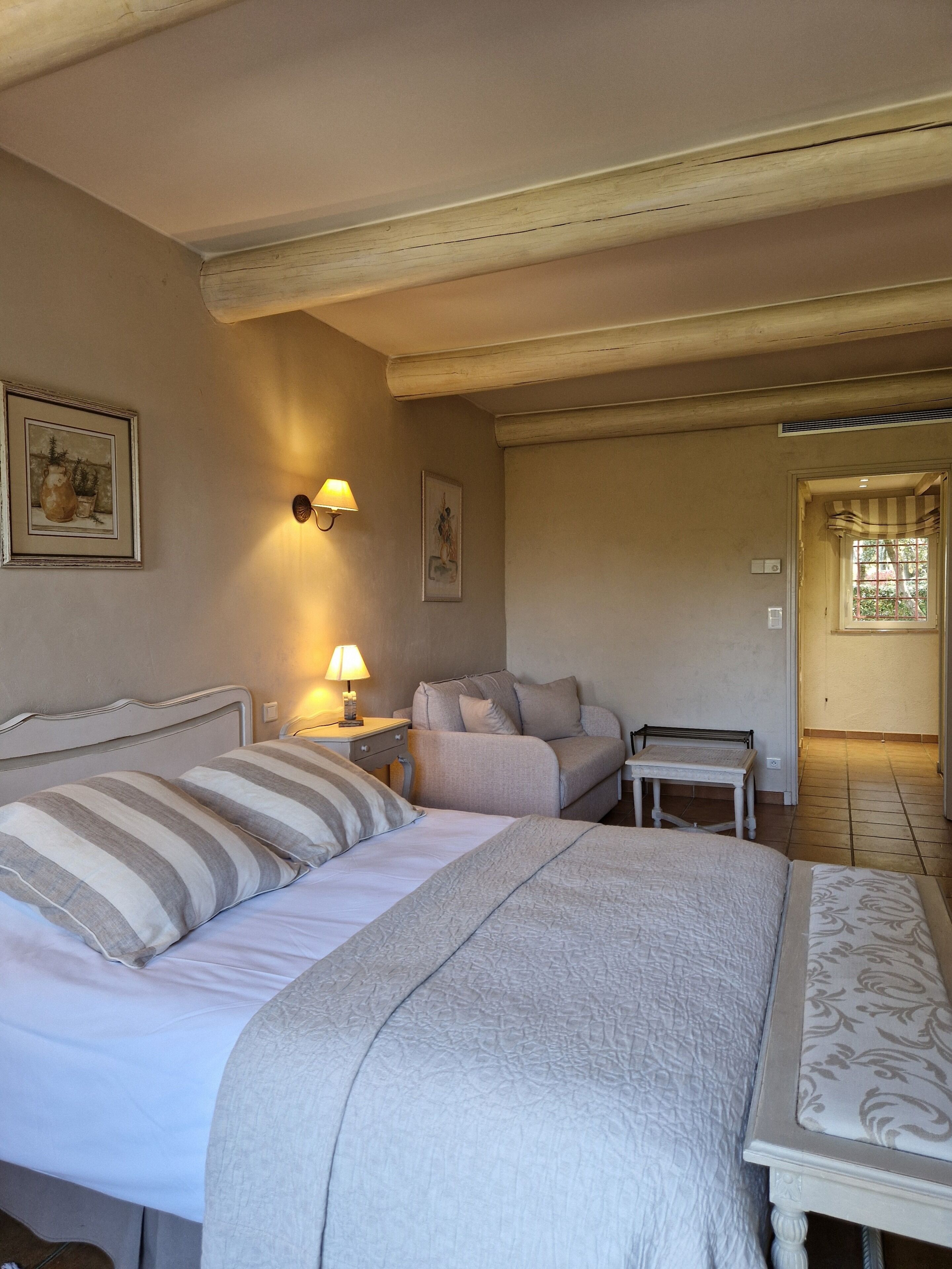 Un dormitorio con cama, mesita de noche, lámpara y sofá.