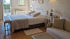 A bedroom with a bed, bedside tables, a sofa, a small table, and a window. - Hotel Mas de Fauchon (Saint-Cannat)
