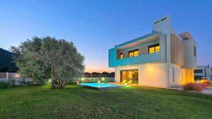A modern two-story house with a swimming pool, surrounded by a well-maintained lawn and a large tree. - Filerimos Villa (Rhodes)