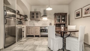 Una cocina con electrodomésticos de acero inoxidable, un armario de madera, salpicadero de azulejos y una mesa con sillas blancas.
