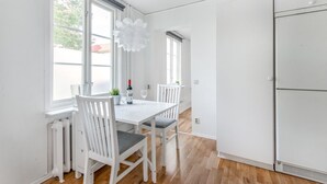 Una cocina moderna con armarios blancos, una mesa de comedor con sillas y un ventanal que proporciona luz natural.