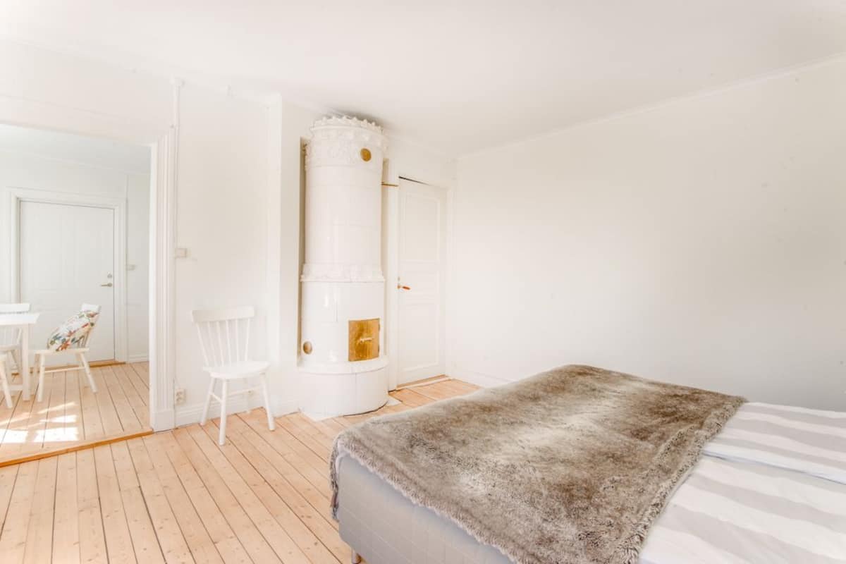A bedroom with a bed, a white fireplace, and a small table with chairs.