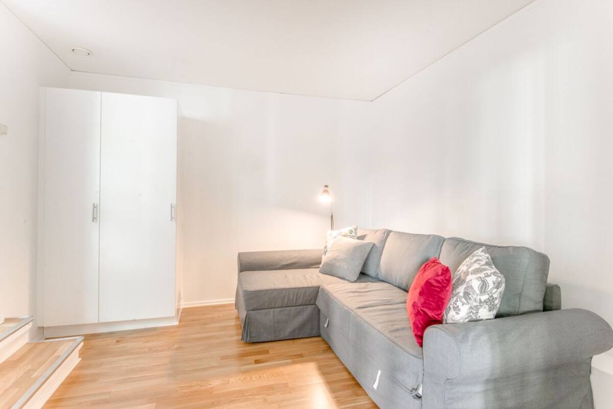 A modern living room with a grey sectional sofa, a white wardrobe, and a floor lamp.