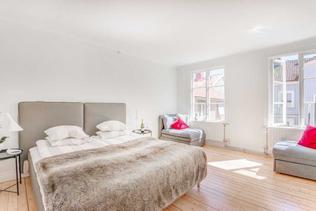 A bedroom with a bed, a chair, a lamp, and a window.