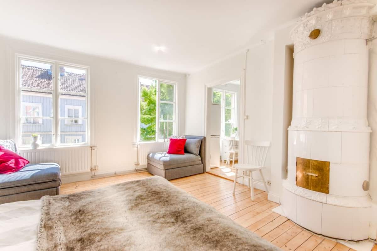 A spacious room with a fireplace, a sofa, a chair, and large windows.