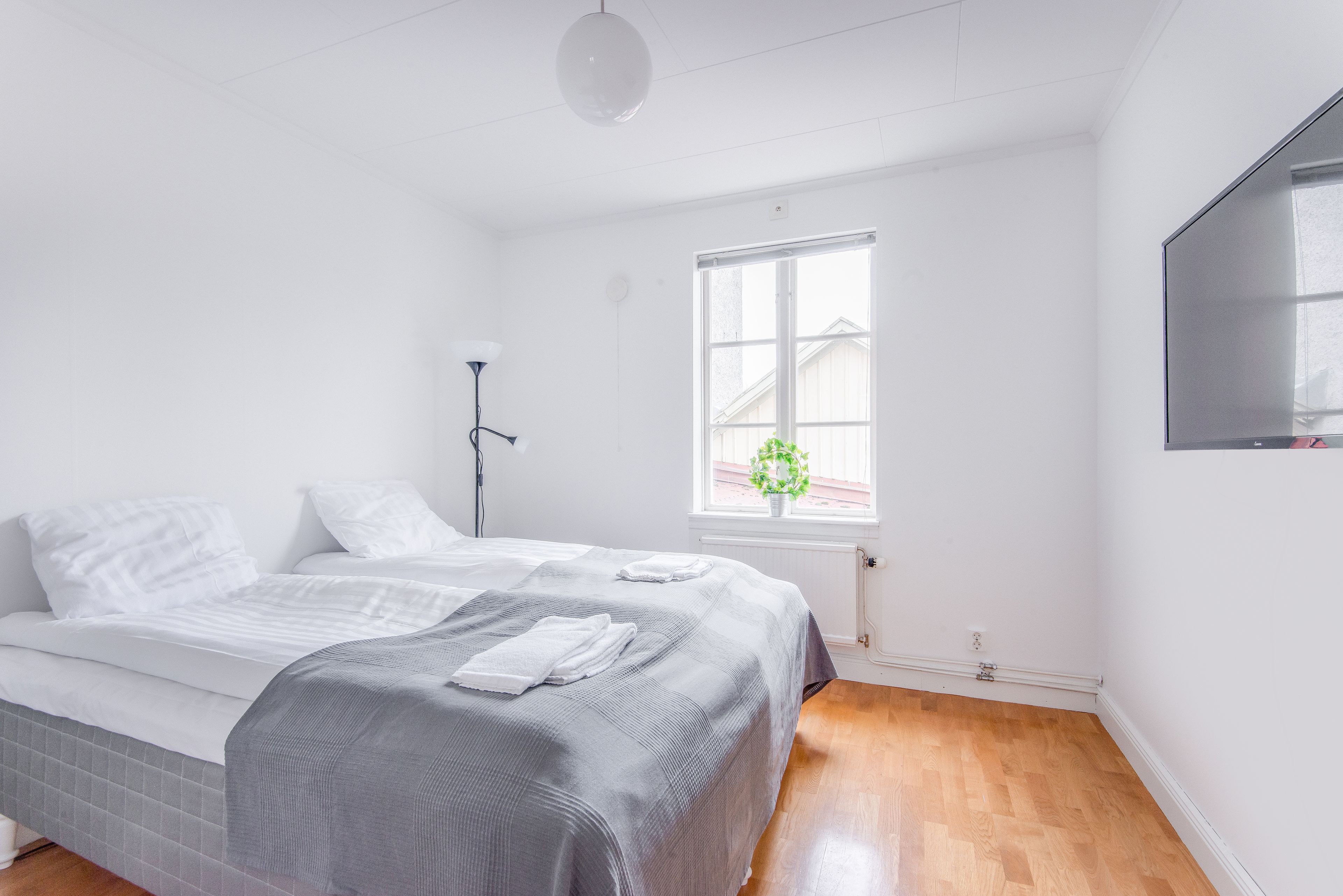 Une chambre à coucher avec un lit, une fenêtre donnant sur un beau paysage, une lampe de chevet et un téléviseur fixé au mur.