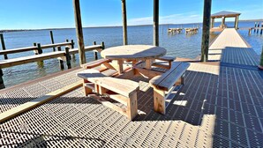 A wooden pier with a picnic table and benches, leading to a dock extending into calm water. - Come get your toes in the sand! Enjoy the Vitamin Sea ☀️ (Orange Beach)