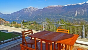 Conjunto de mesa e cadeiras de madeira em terraço, vista para as montanhas.