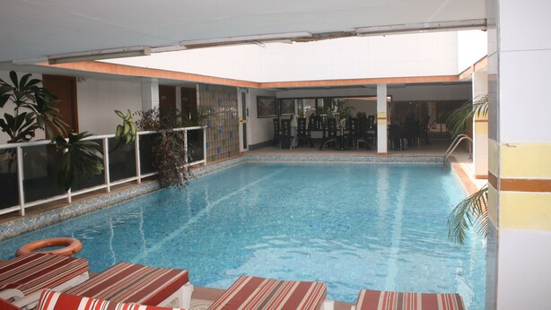 En indendørs swimmingpool med liggestole og potteplanter.