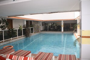 Ein Hallenbad mit Liegestühlen und Topfpflanzen.