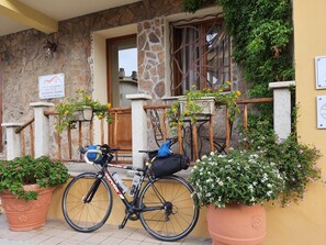 A bicycle parked outside a building with a stone facade, a sign indicating 'Best to Breakfast Al Poz', and potted plants. - Al Pez Exclusive Rooms (Olbia)