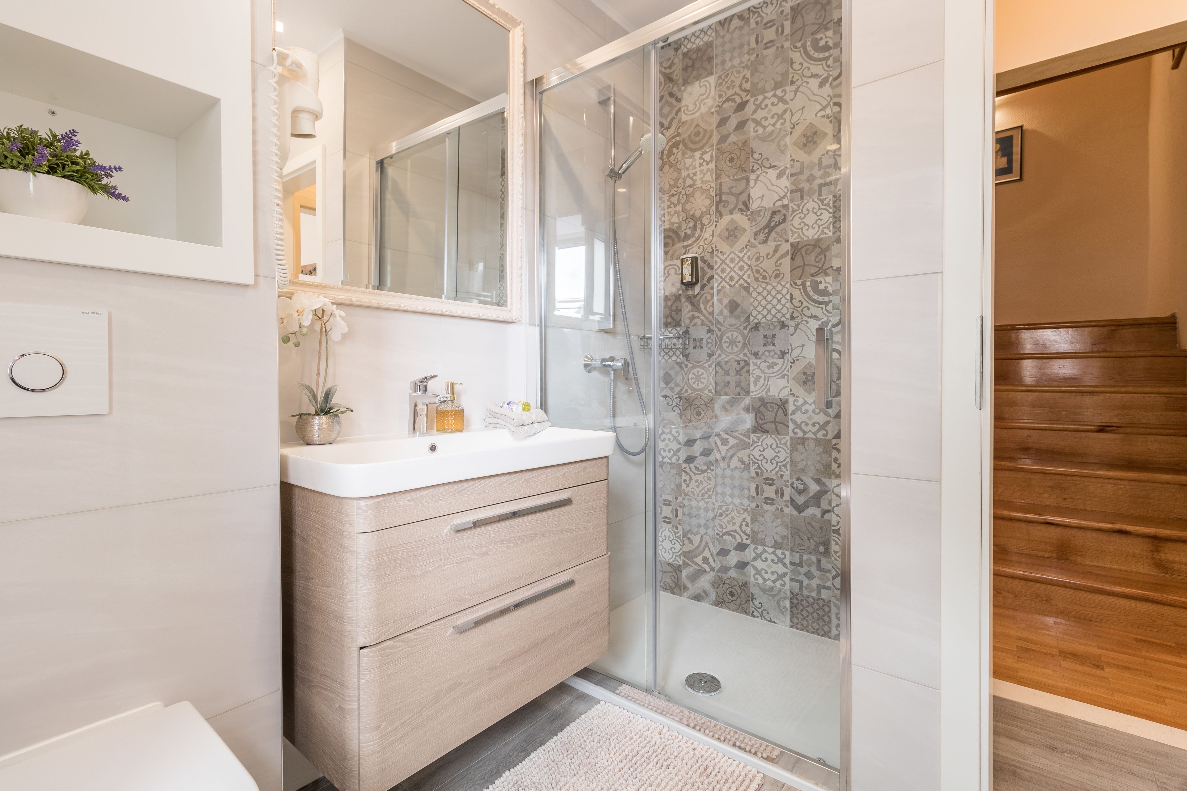 A modern bathroom with a glass shower, a wooden vanity, and a mirror above the sink.