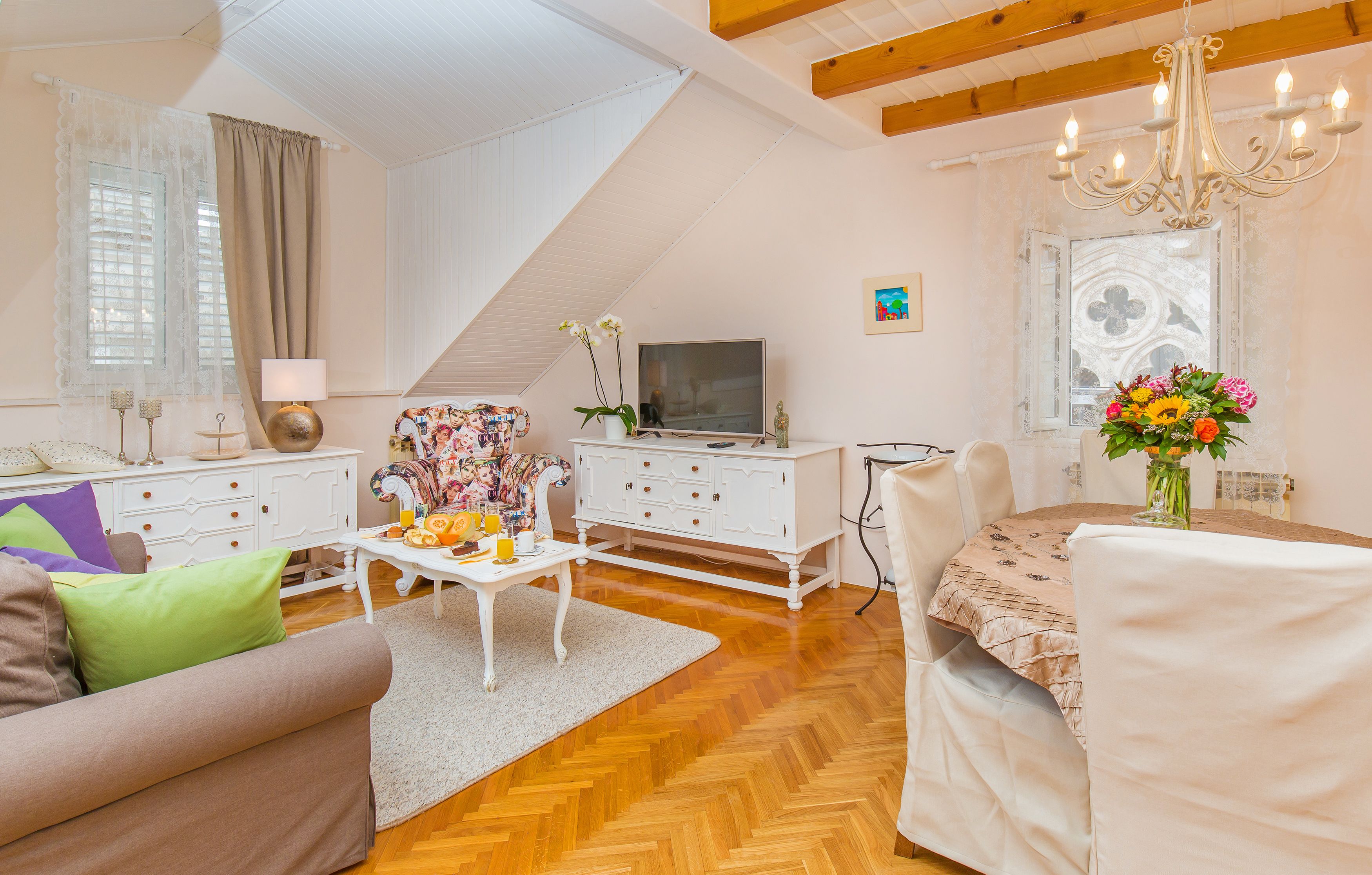 A living room with a sofa, coffee table, TV, and a dining area with chairs and a table.