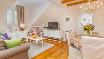 A living room with a sofa, coffee table, TV, and a dining area with chairs and a table.