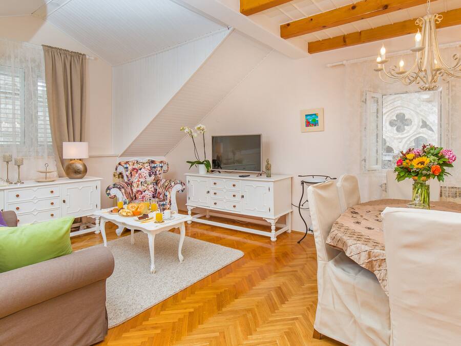 A living room with a sofa, coffee table, TV, and a dining area with chairs and a table.