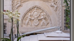 Una ventana con vistas a un muro de piedra que presenta un relieve escultórico.