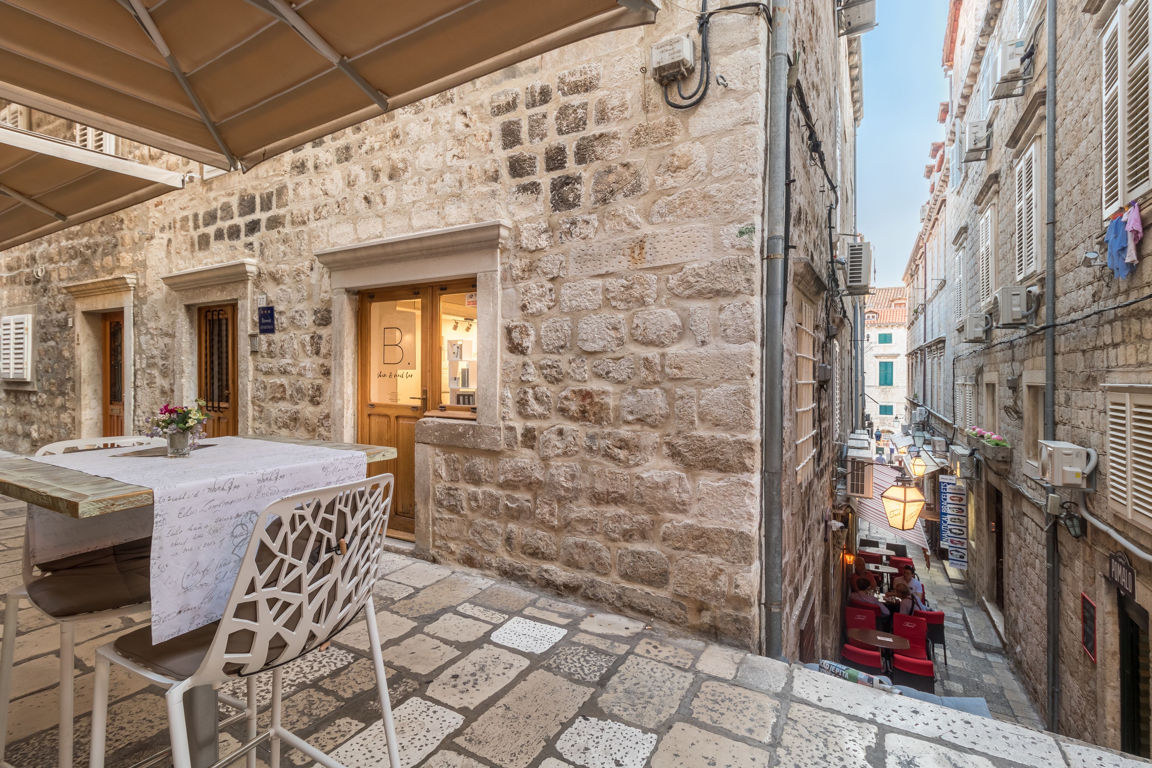 Un bâtiment en pierre avec une table et des chaises disposées pour permettre de prendre les repas en plein air.