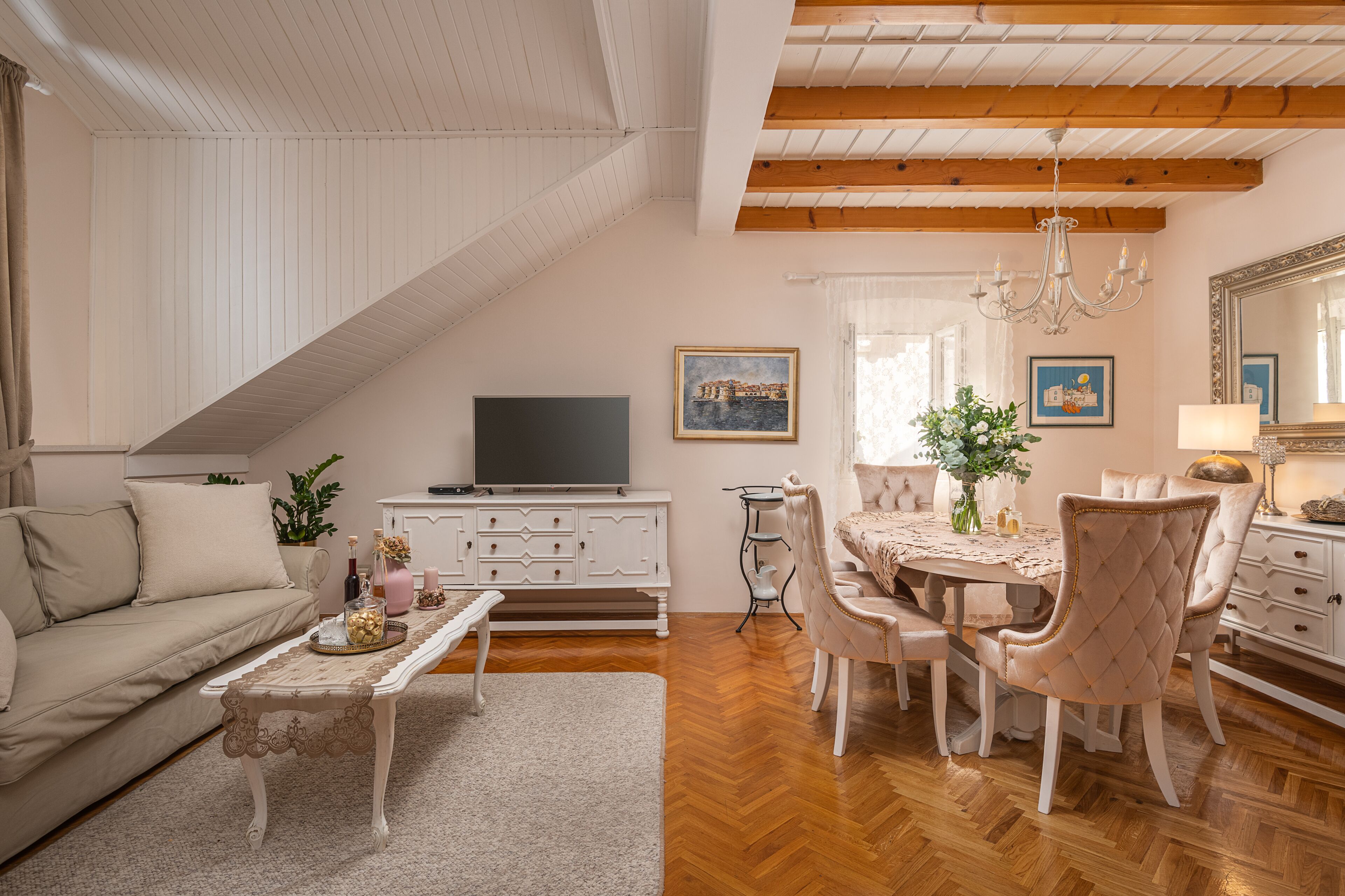 Una sala de estar con sofá, mesa de centro y televisor, un comedor con mesa y sillas, y un espejo grande.