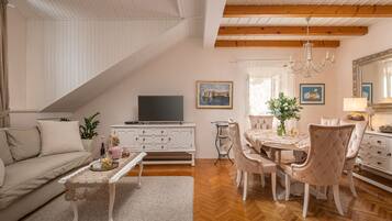 Una sala de estar con sofá, mesa de centro y televisor, un comedor con mesa y sillas, y un espejo grande.