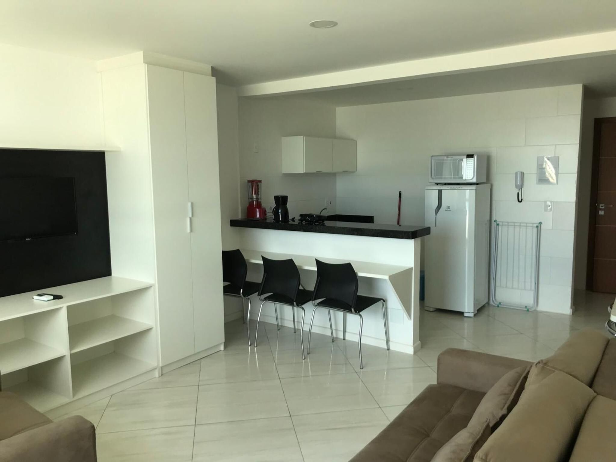 A modern living room with a flat-screen TV, a sofa, and a dining area with chairs.
