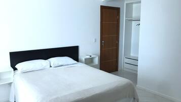 Quarto com cama, mesa de cabeceira, porta de madeira e closet espaçoso.