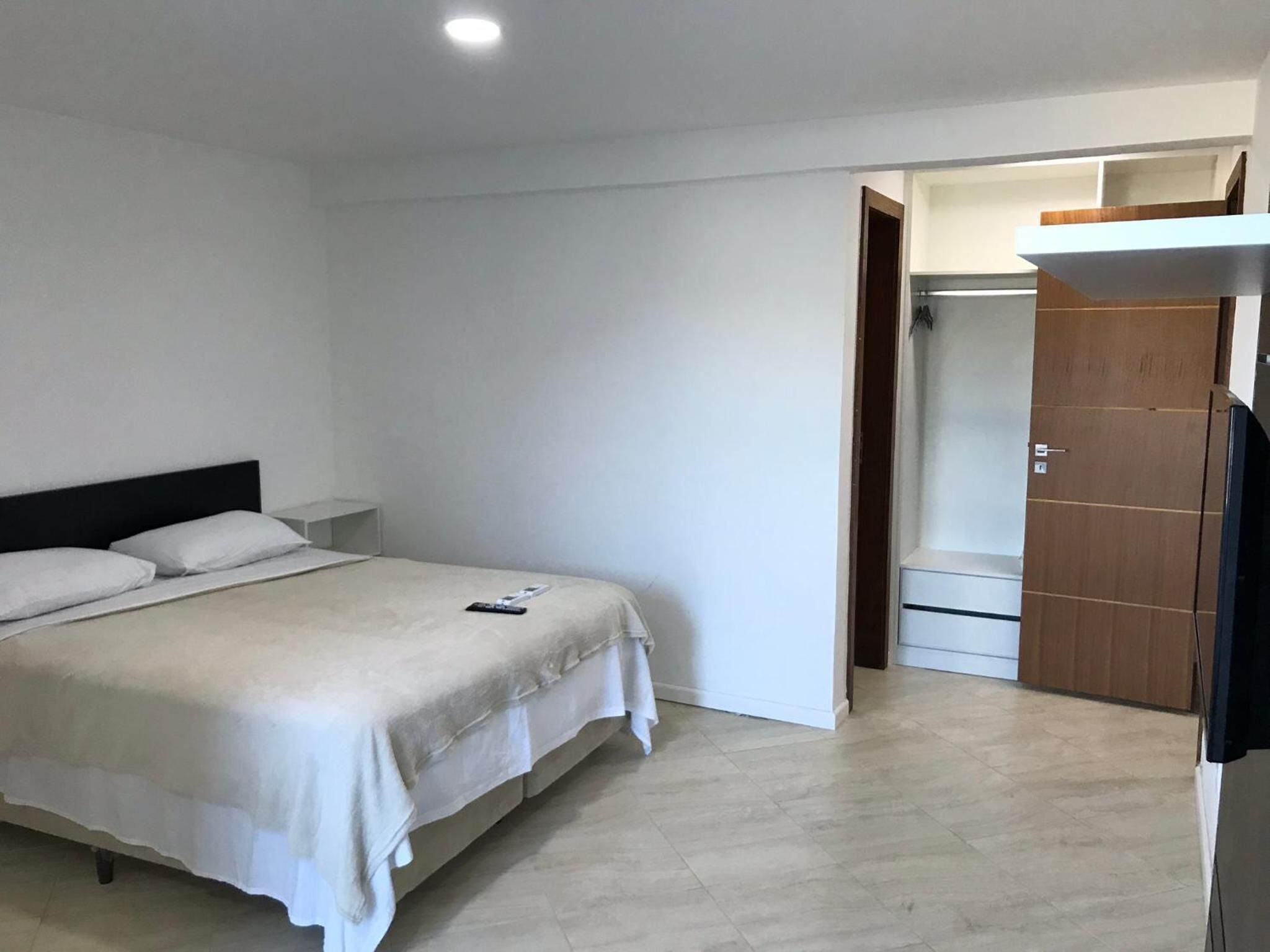 A bedroom with a bed, a nightstand, a wardrobe, and a door leading to a bathroom.