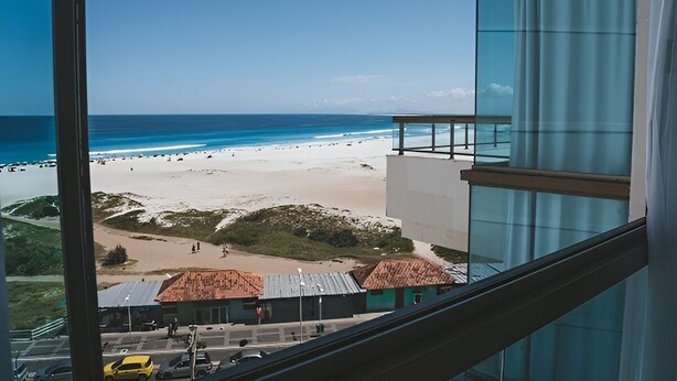 A view from a high-rise building overlooking a beach with a clear sky. - Sophia II Residence Inn (Arraial do Cabo)