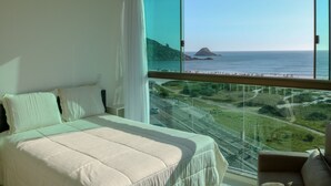 A bedroom with a large window overlooking a coastal landscape. - Sophia II Residence Inn (Arraial do Cabo)