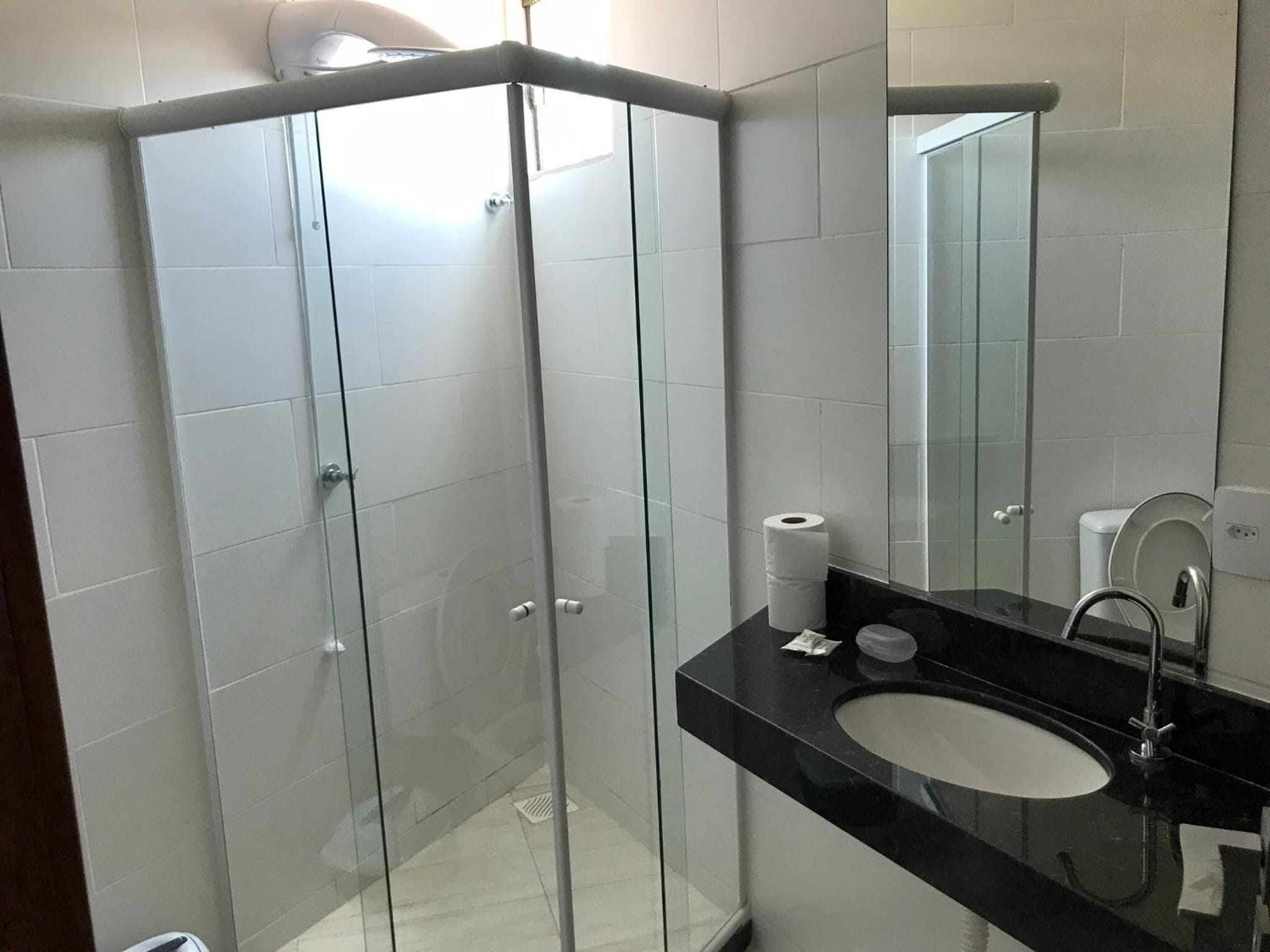 A modern bathroom with a glass-enclosed shower, a black countertop sink, and a mirror.