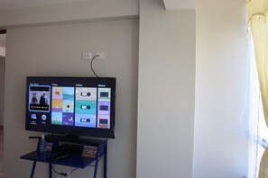 En tv-skärm som är monterad på en vägg och visar ett användargränssnitt med kategorier som till exempel ”Populär musik”, ”Foton”, ”Videor” och ”Musik”.