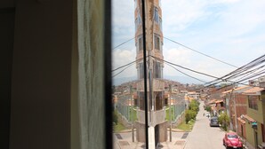 Blick durch ein Fenster auf eine Wohnstraße mit einem hohen Gebäude im Hintergrund.