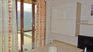 A room with a view of the sea, a wooden table, a white chair, and a cabinet. - La Quiete 29 Holideal (Tremosine)